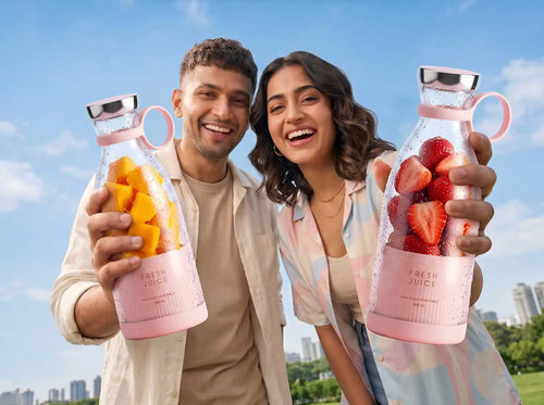 Happy couple holding portable blender bottles outdoors for fresh juice on the go